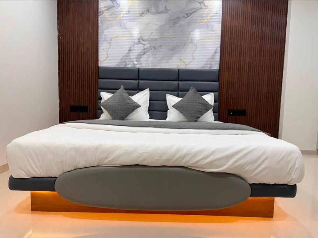 a bedroom with a large bed with a black headboard at Hotel Peacock Anand in Anand