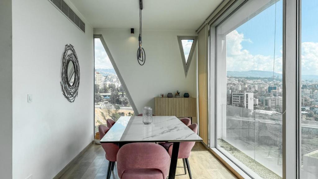 a dining room with a table and chairs and a large window at The Cube 10, 3-BR in Sin El Fil in Beirut