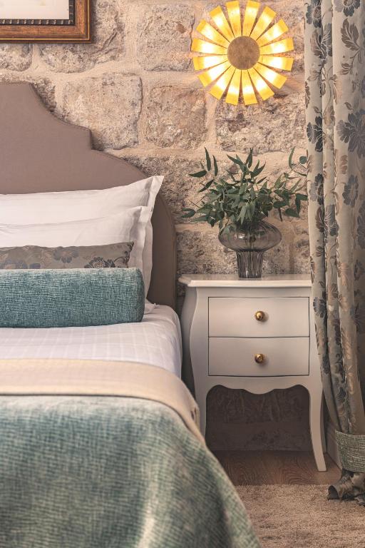 a bedroom with a bed and a plant on a night stand at Dominus Little Palace in Dubrovnik