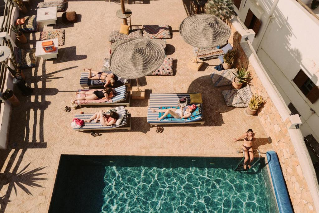 an overhead view of a group of people laying around a swimming pool at Surf and Friends in Tamraght Ou Fella