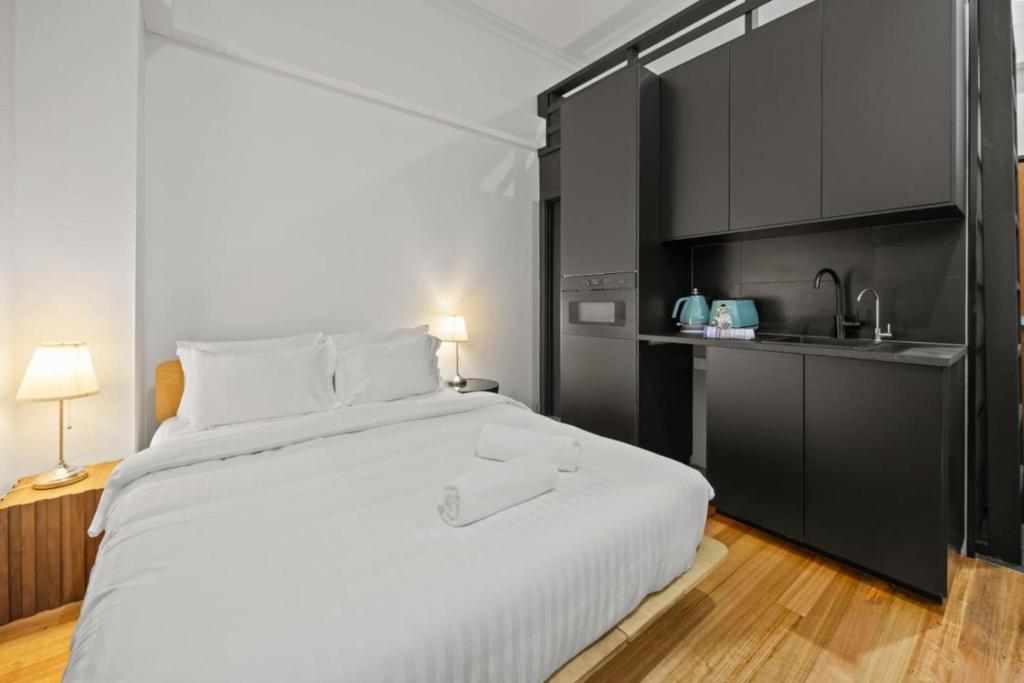 a bedroom with a large white bed and a kitchen at South Beach Studio - Simple Base, Walk Everywhere in South Fremantle
