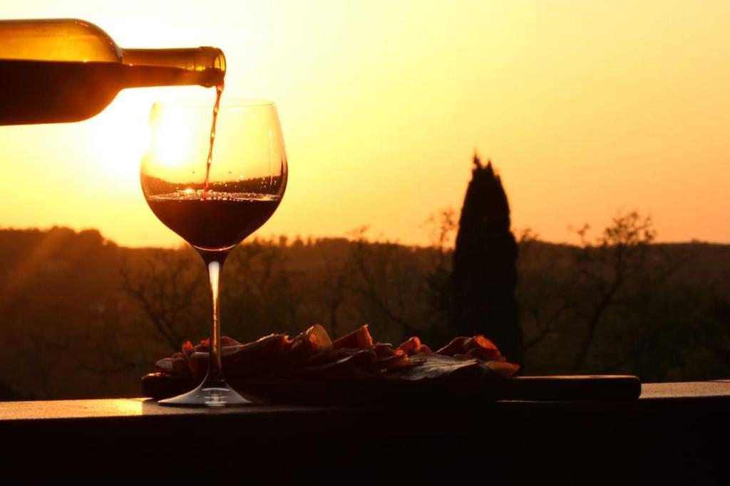 a bottle of wine being poured into a wine glass at Tuscan Sunsets Tramonti Toscani in Fauglia