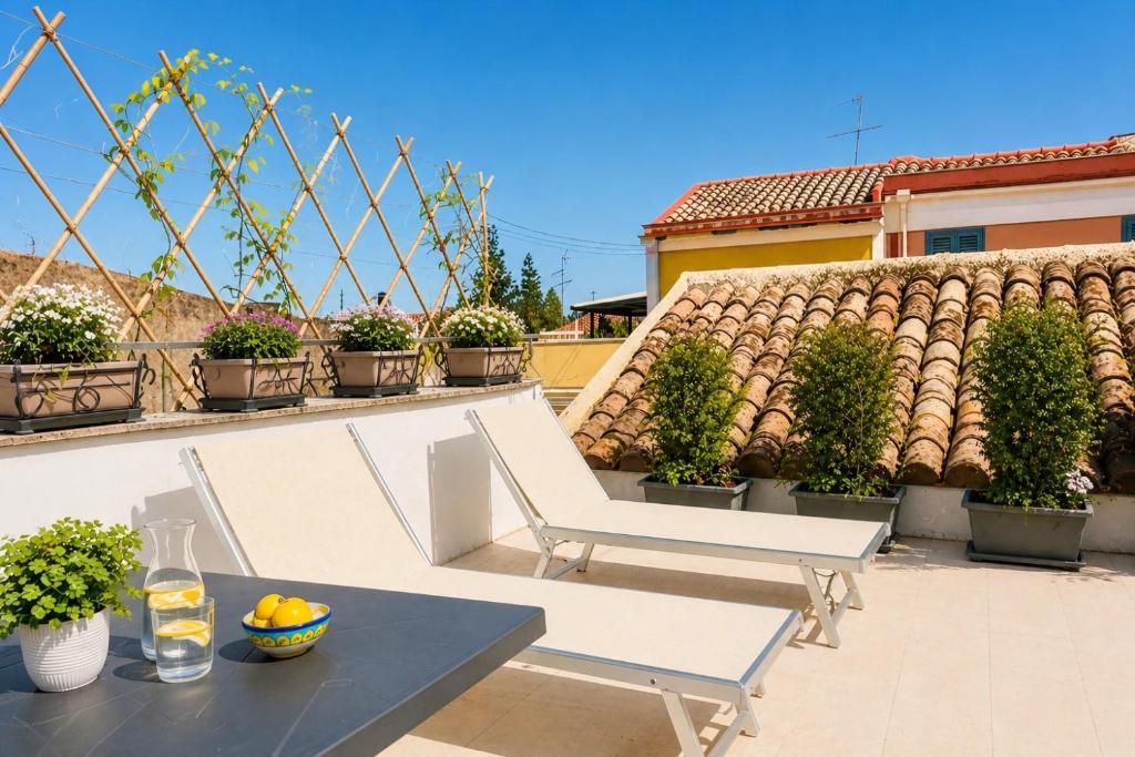 a patio with two white chairs and a table at MSuite Etna Sicily in Macchia