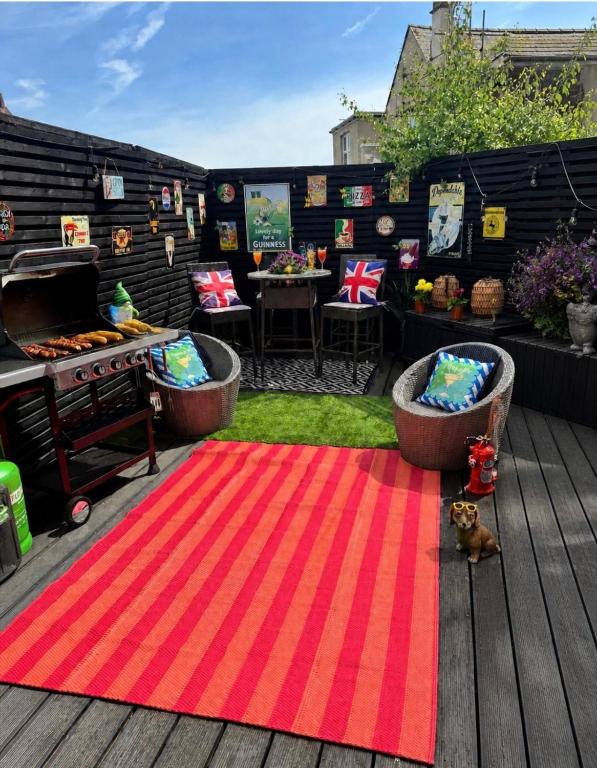 a patio with a red rug and a grill at Coastal Nest in Hollington