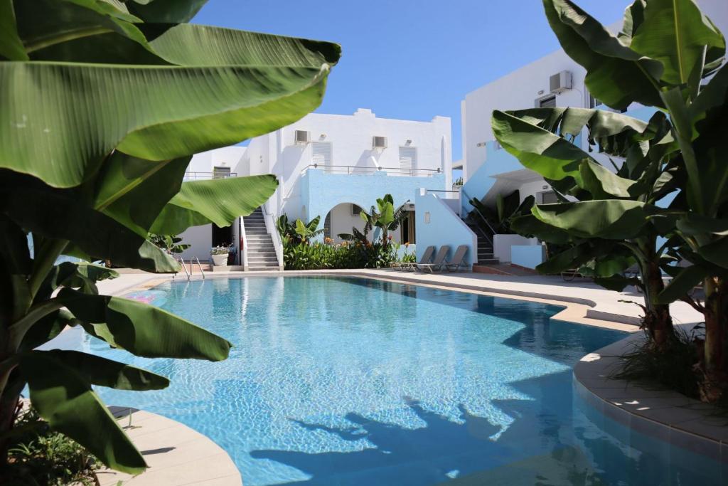 a swimming pool with blue water and green plants at Platanes Hotel Apartments Rethymno in Platanes