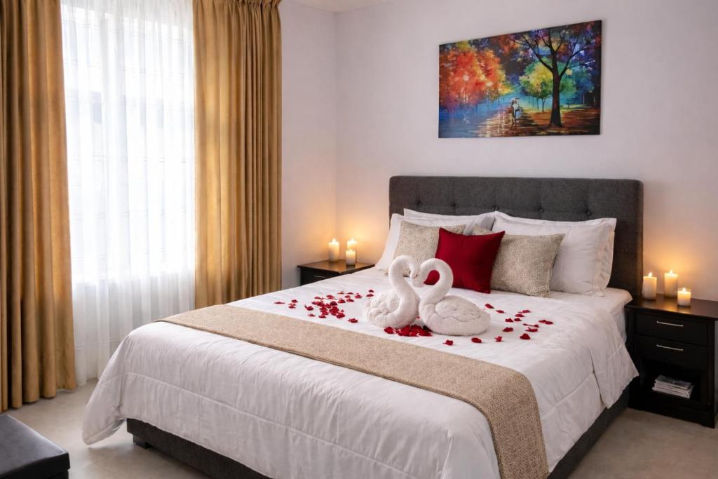 two swans sitting on a bed with roses on it at HOTEL BIG BEN MALAGA SANTANDER in Málaga