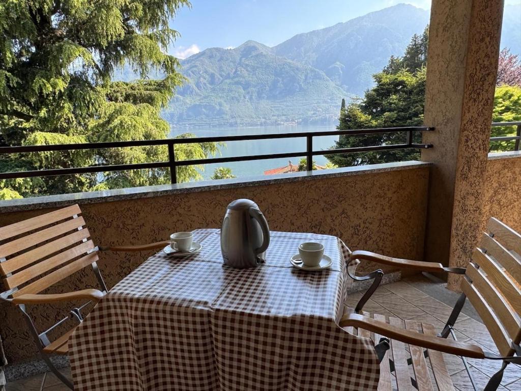 a table with two cups and a tea kettle on a balcony at Limonta, Fiori e Lago Private Apartment in Limonta
