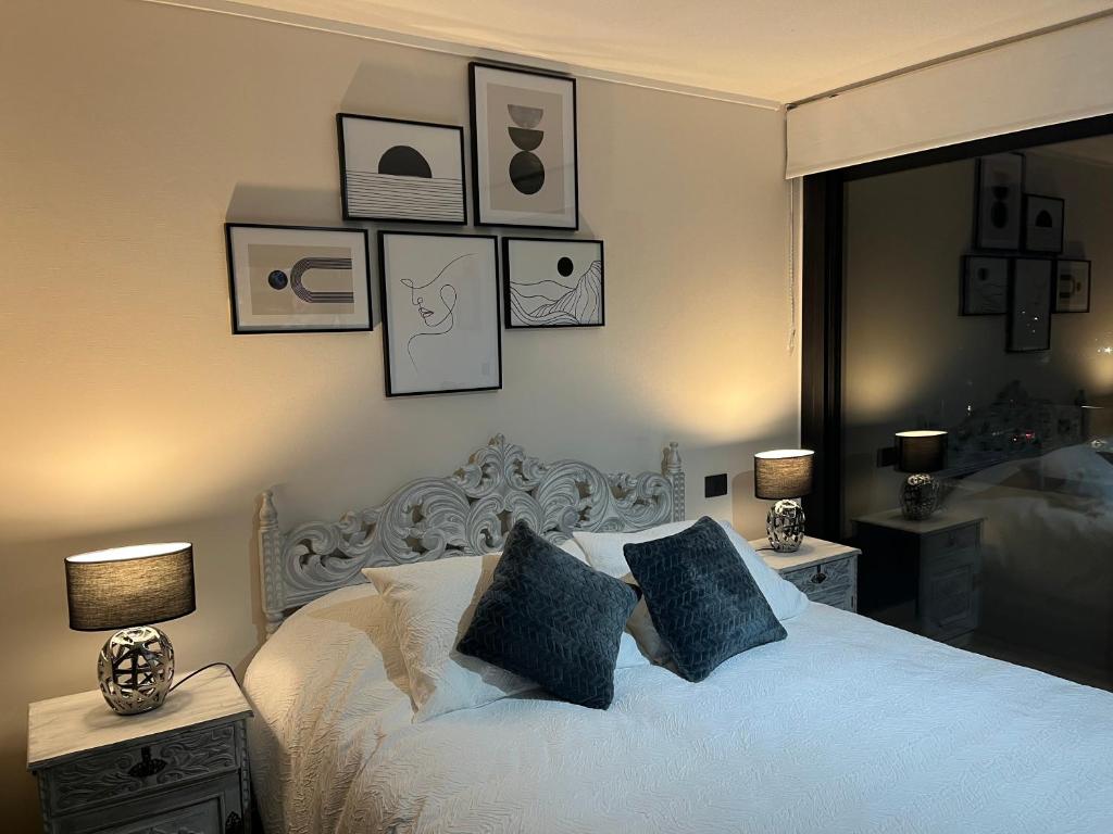 a bedroom with a white bed with pictures on the wall at Ápice del bosque in Temuco