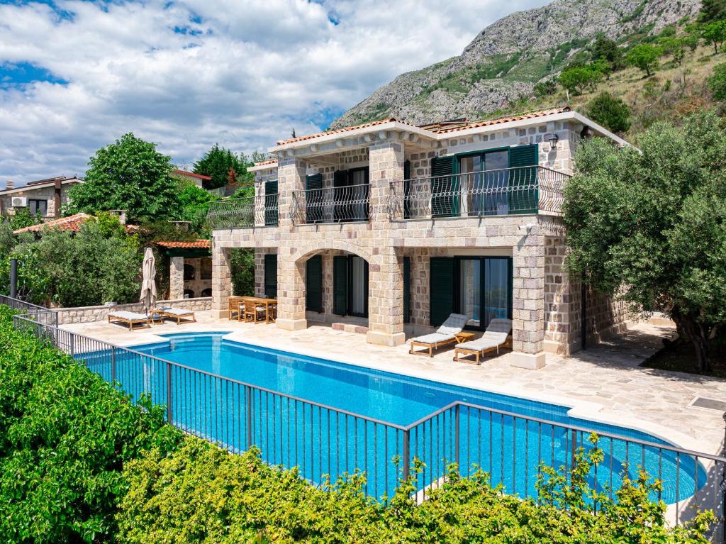 a house with a swimming pool in front of a mountain at Villa Azzurra in Krstac