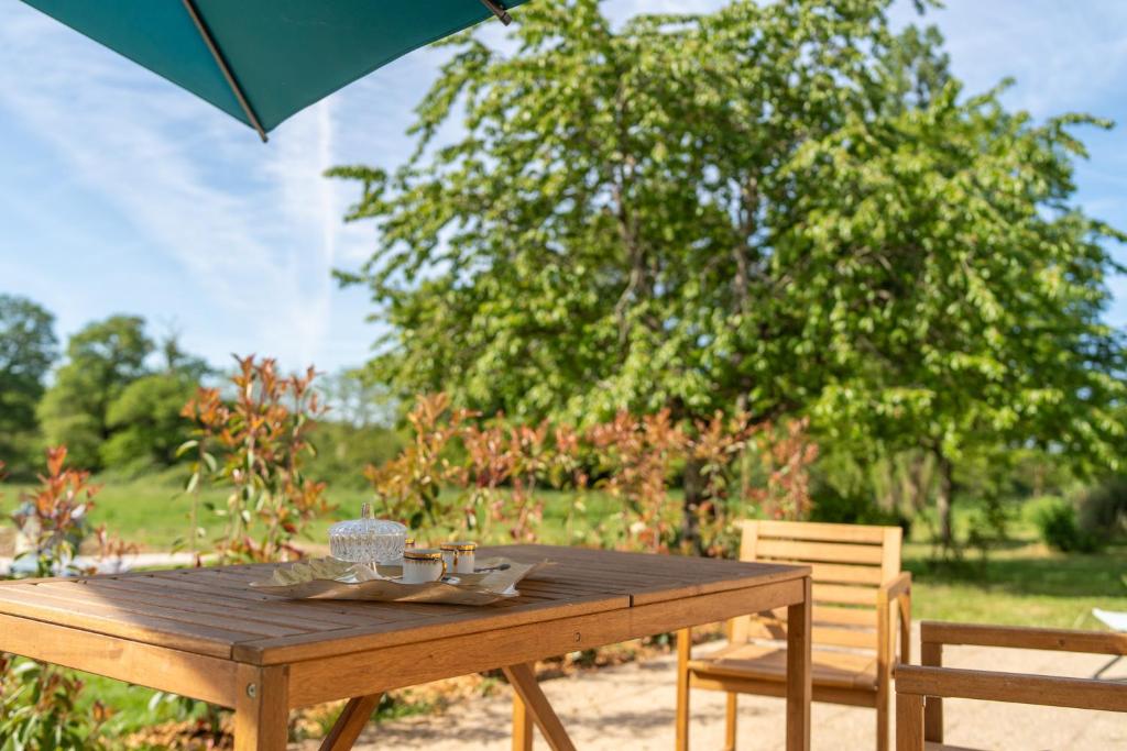 a wooden table with an umbrella and two chairs at Domaine du Riadoux in Bonneuil