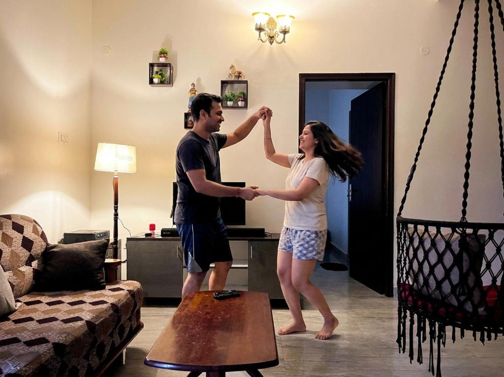 a man and woman standing in a living room holding hands at Payaringal House Botanical Garden White Town Promenade Beach in Pondicherry
