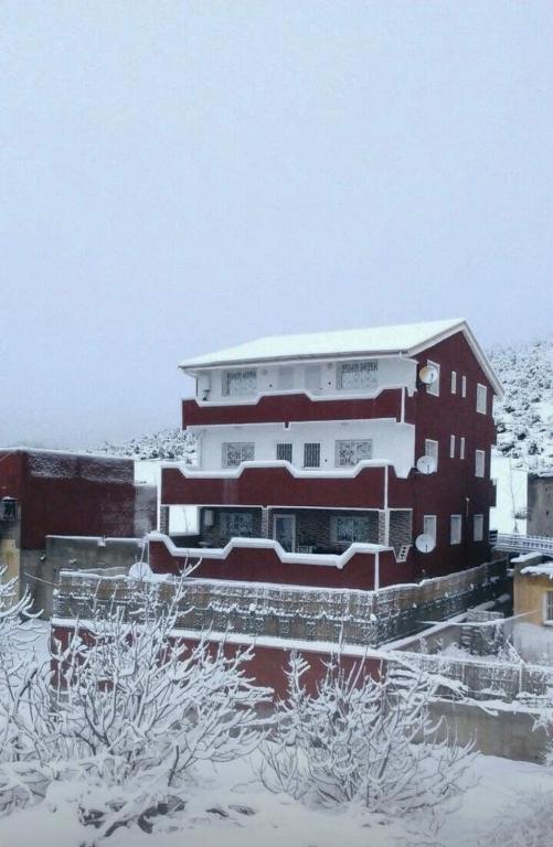 a building with snow on the ground in front of it at Dar Idurar in Imouzzer du Kandar