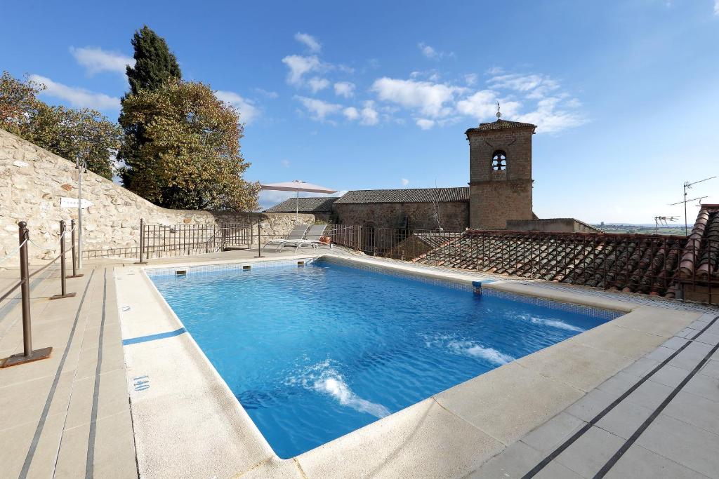 una piscina con torre dell'orologio sullo sfondo di Eurostars Palacio de Santa Marta a Trujillo