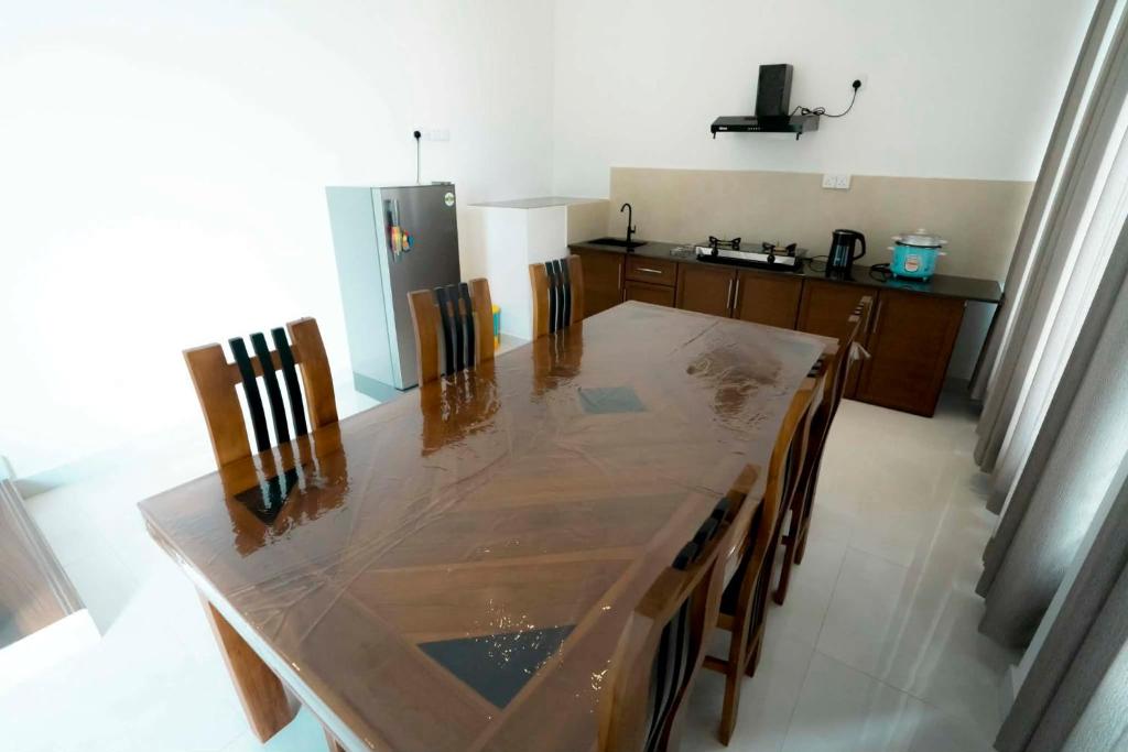 a kitchen with a table with chairs and a refrigerator at Prime Inn Kandy in Kandy