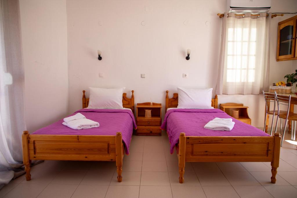 two beds in a room with purple sheets at Fay's Studios Leros in Lakkíon