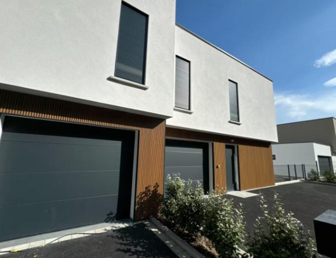 a building with two garage doors and a car lot at Les Villas de l'Ill in Didenheim