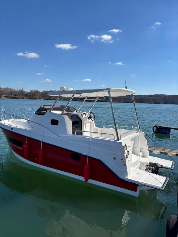 a red and white boat sitting in the water at Silent Jacht Solina in Polańczyk