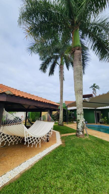 a hammock sitting next to a house with palm trees at Hotel dos Príncipes - Guarujá in Guarujá