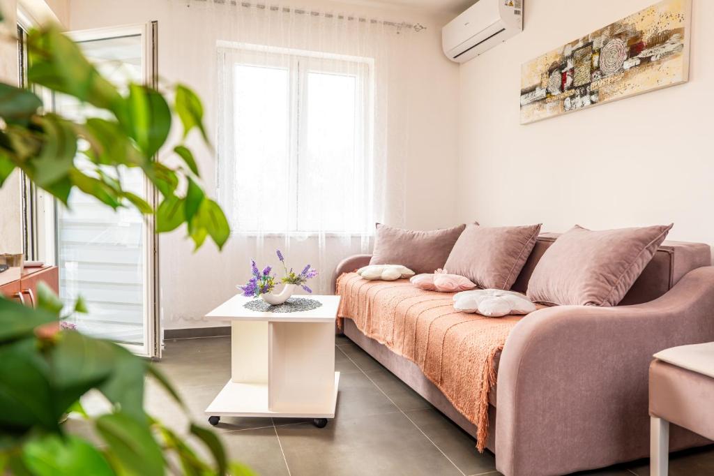 a white living room with a bed and a table at Apartman Goga 2 in Veliko Gradište