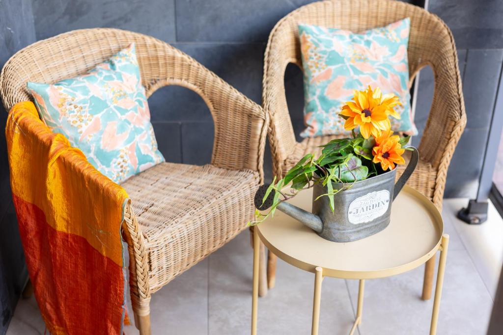 two wicker chairs and a table with a vase with flowers at Enjoy life in our apartment. Wifi Parking in Guardamar del Segura