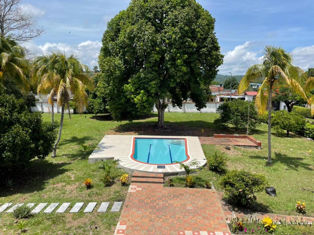 a swimming pool in a park with a tree at Casona El Remanso in Mariquita