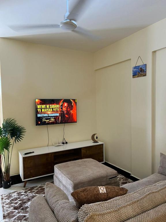 a living room with a couch and a tv on the wall at Mimi Home Stays in Voi