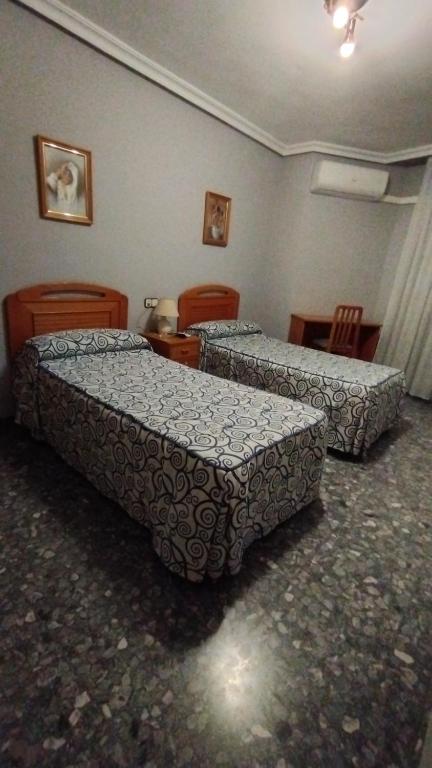 two beds in a room with chairs and tables at Hotel Vista Alegre in Torredonjimeno