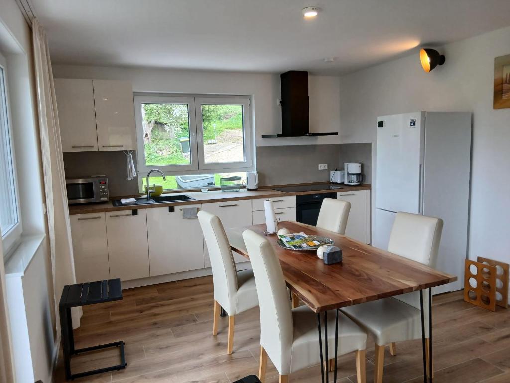 a kitchen with a wooden table and white chairs at Ferienwohnung Buchenblatt in Simmerath