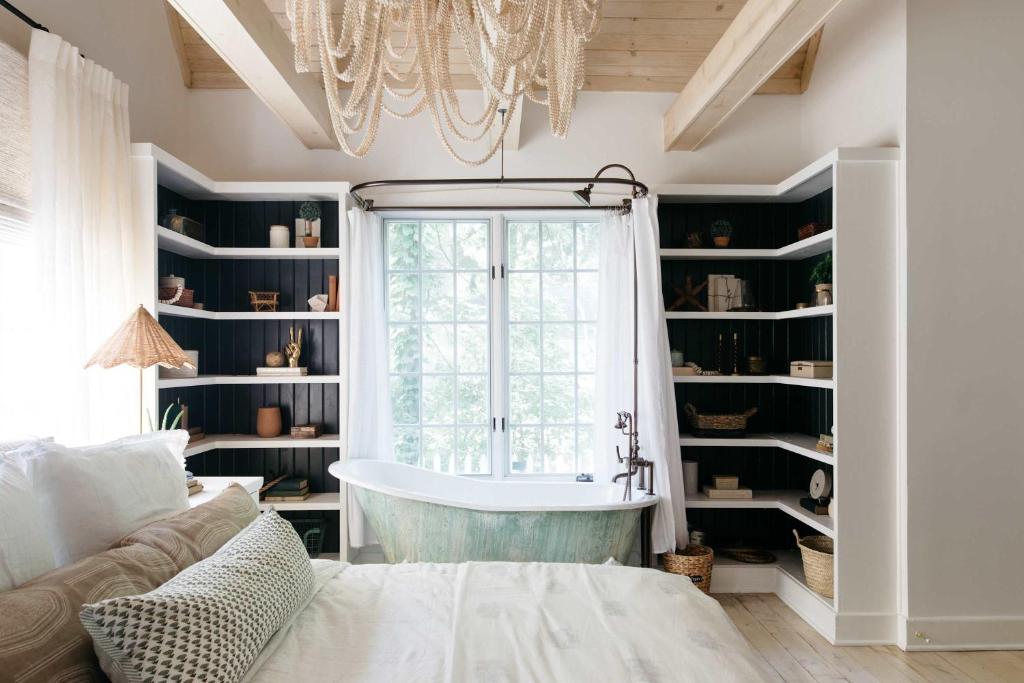 a bath tub in a room with a chandelier at Leo Cottage by Juniper Holiday + Home in Union Pier