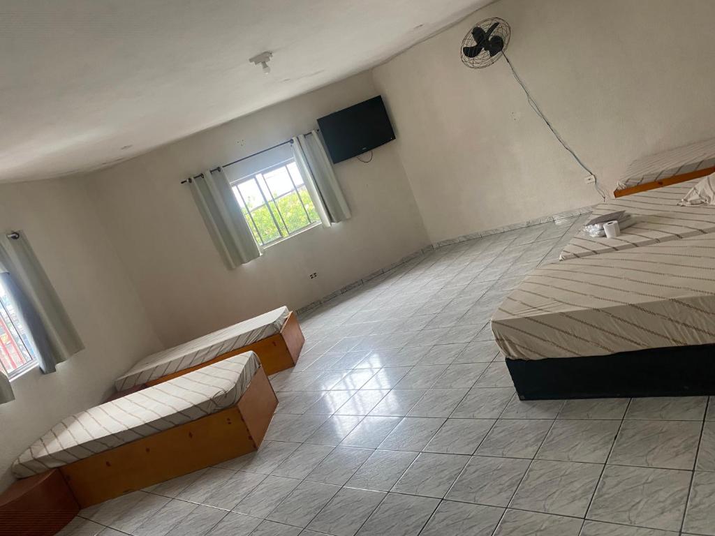 a room with two beds and a tv in it at Hospedaria São Mateus in São Paulo