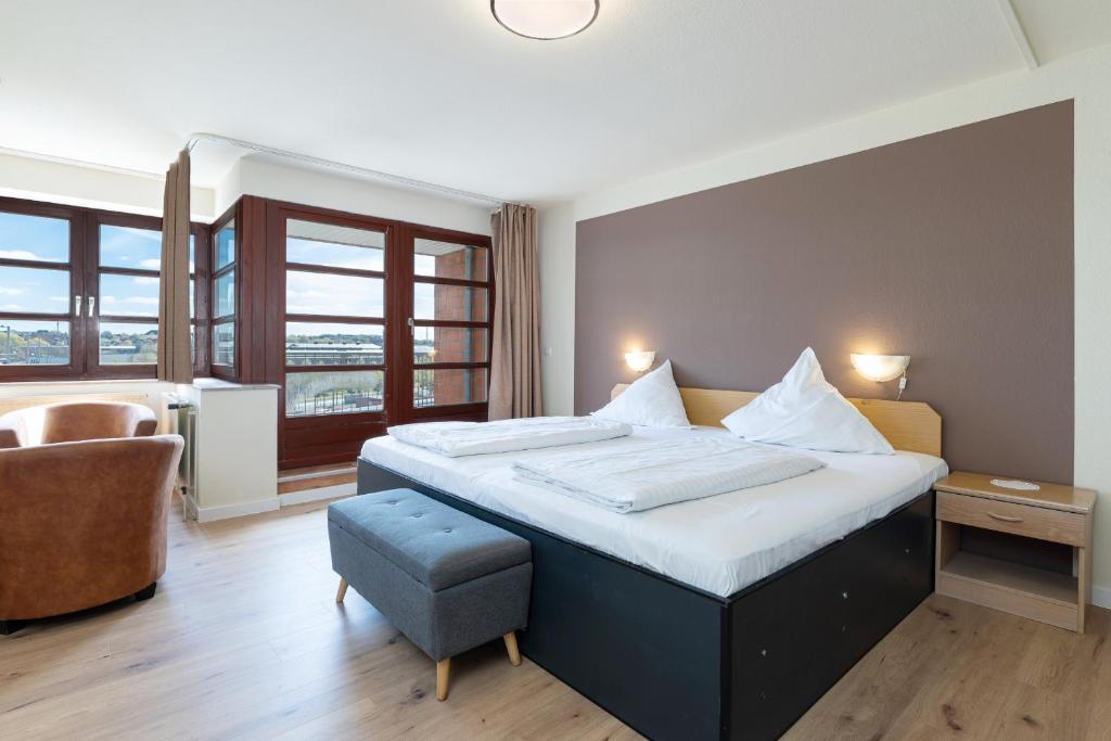 a hotel room with a large bed and a chair at Hotel an der Hörn in Kiel