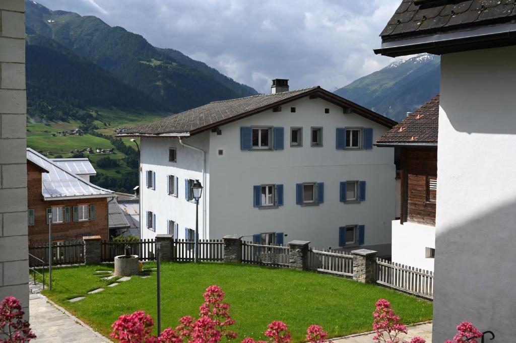 a white house with a fence and a green yard at Ferienwohnung "Posta Veglia" - Cumbel in Cumbels