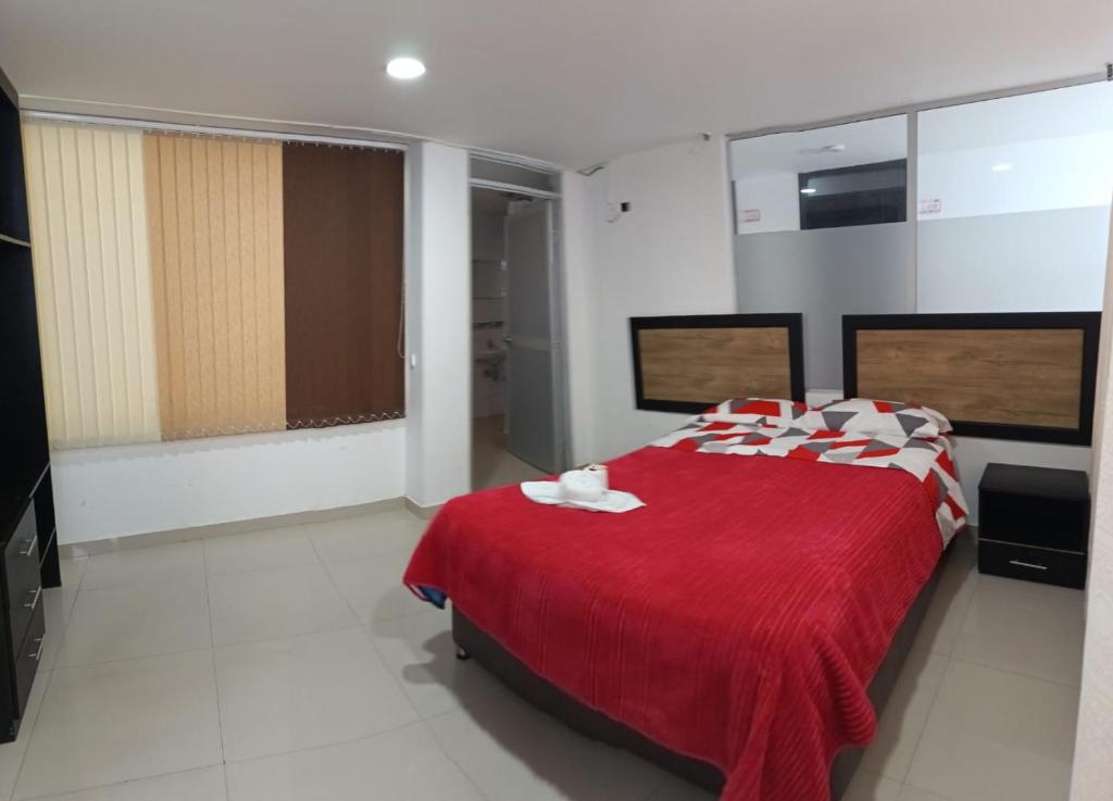 a bedroom with a red bed with red and white pillows at Hotel the Blue House in Ipiales