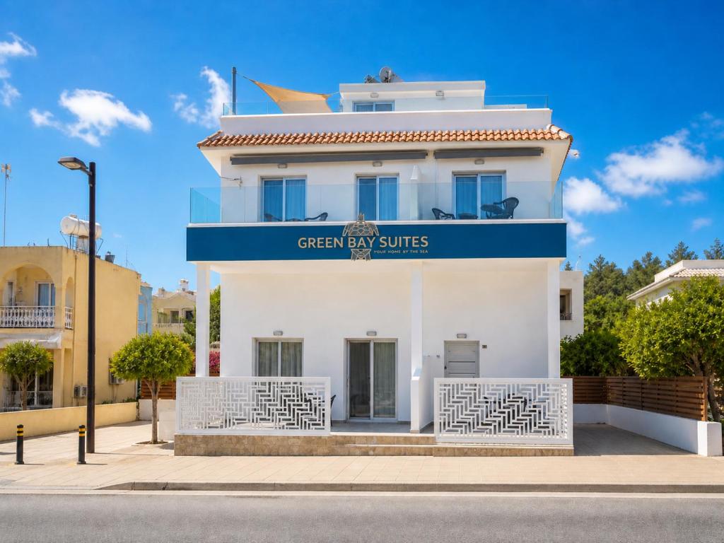 a white building with a blue sign on it at Green Bay Suites in Protaras