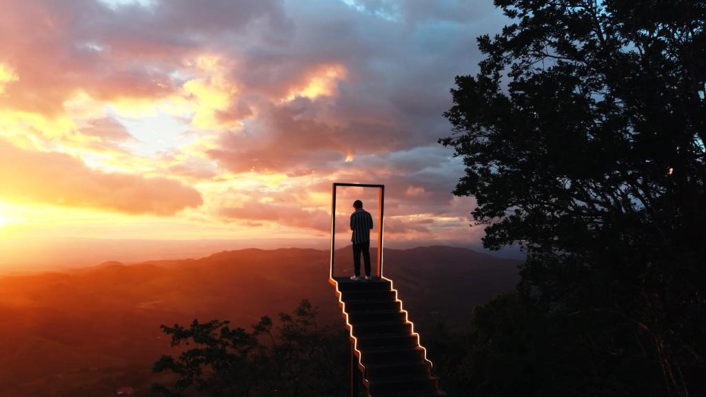 a man standing on a door on top of a mountain at Amalú Luxury View Cabins in Monteverde Costa Rica
