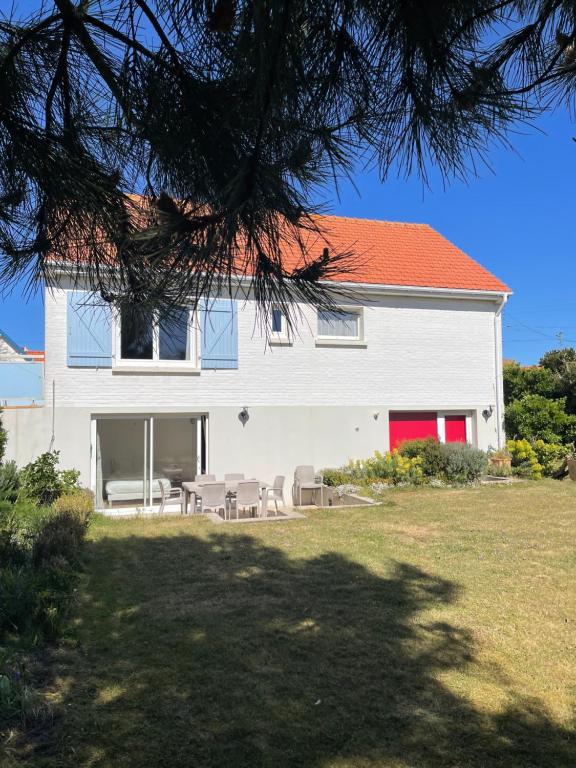 a white house with a red roof and some chairs at Le Clos - Proximité plage in Ambleteuse