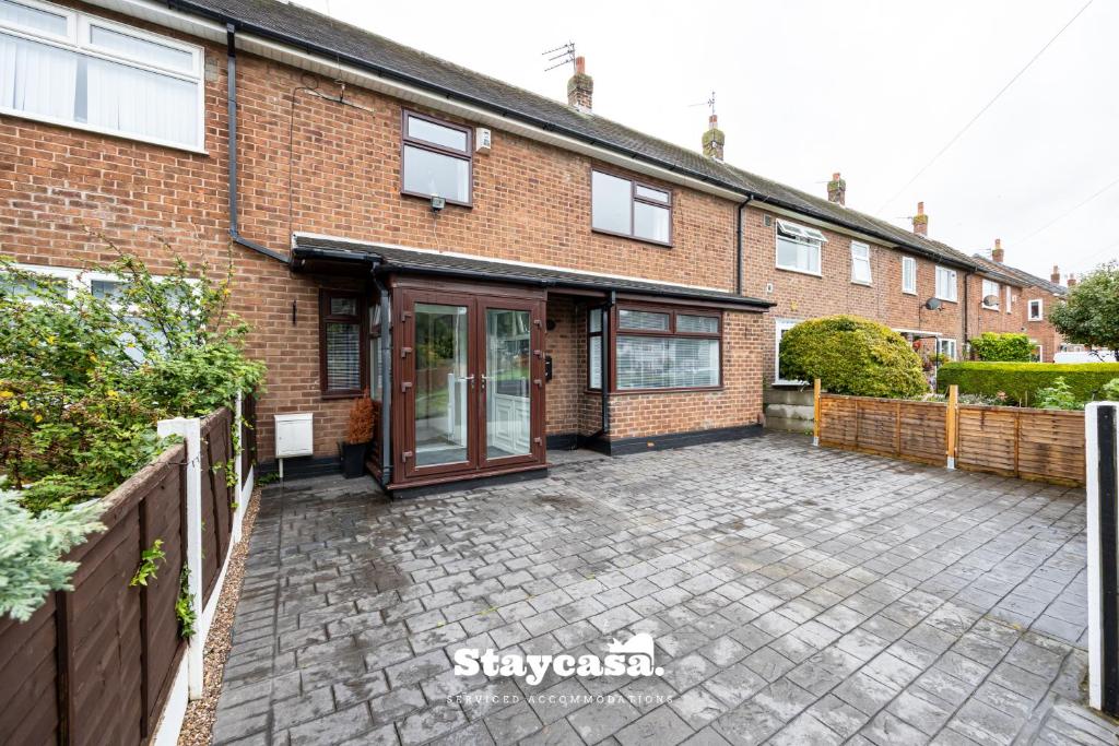 a brick house with a patio in front of it at Spacious Cosy Cove with Large Driveway and Garden in Wythenshawe