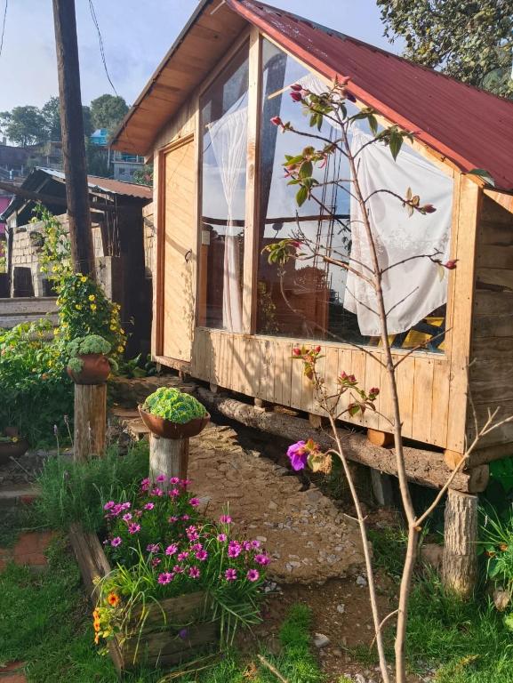 a small wooden house with flowers in the yard at Cabañas Alma Serrana in San Jose del Pacifico