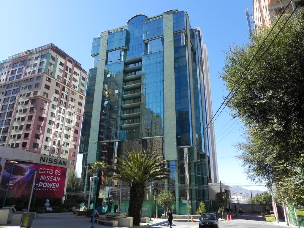 a tall glass building with a palm tree in front of it at Muy cerca, a pasos de la Embajada de EEUU in La Paz