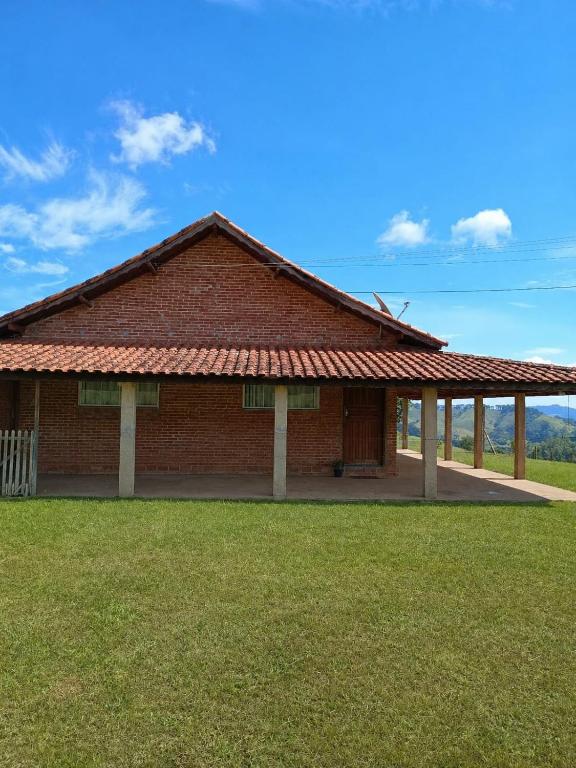 a large brick building with a grass field at Sitio Vale Verde da Serra in Monte Verde
