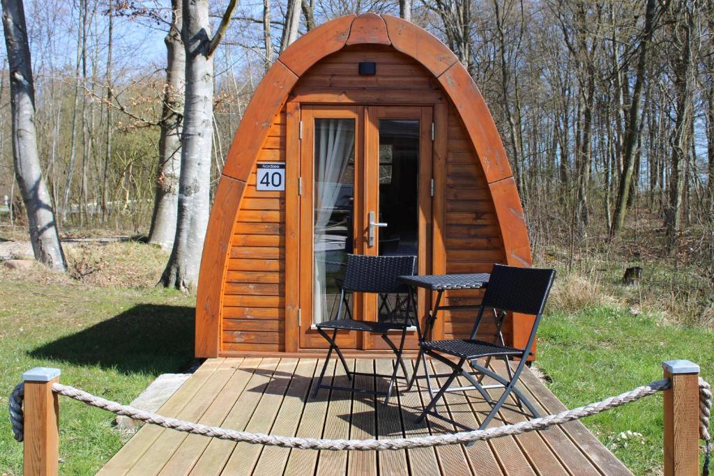 a small wooden cabin with two chairs and a table at 40 Mini Pod "Nordsee" in Silberstedt