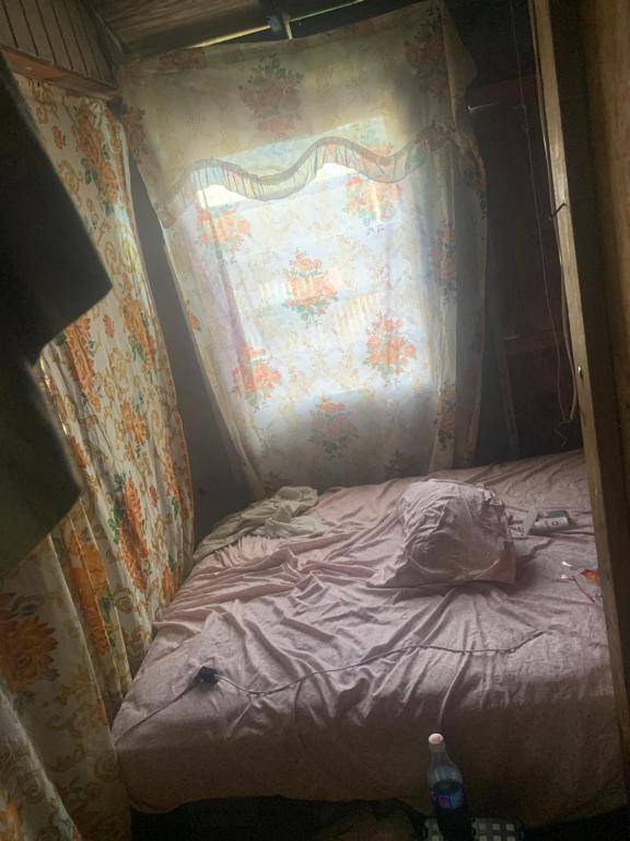 a small bed in a room with a curtain at Good home in Codrington Village