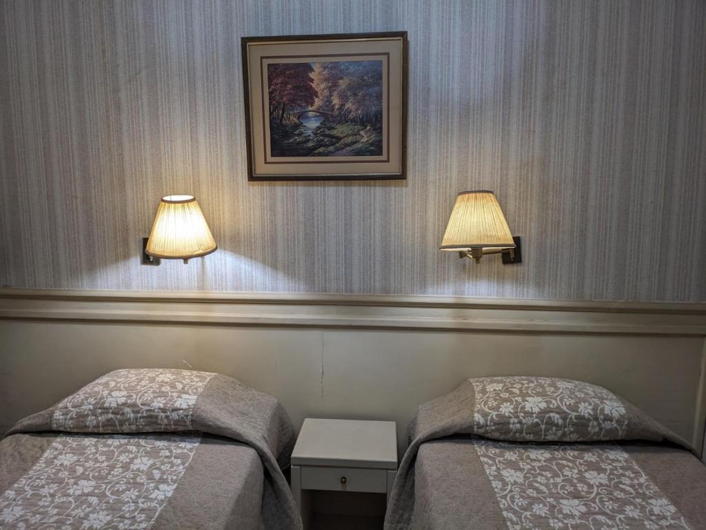 two beds in a room with two lamps on the wall at Hotel Armele Asunción in Asunción
