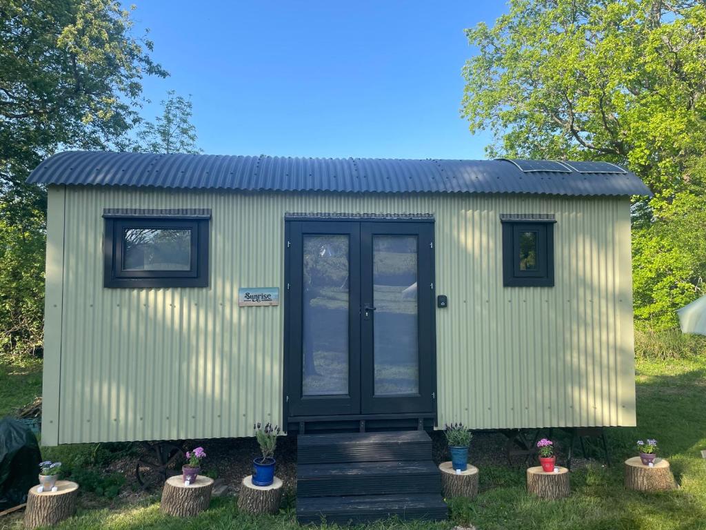 a green tiny house with a black door at Apple Orchard Shepherd Huts in Staple Cross