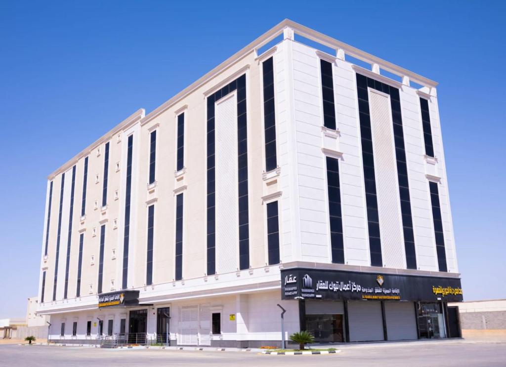 a large white building with black windows on a street at iqama mumayyaza الإقامة المميزة للشقق المخدومة - إقتصادي in Tabuk