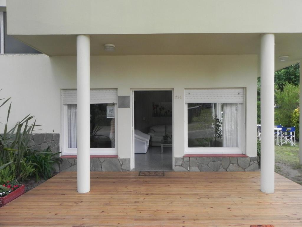 un porche de una casa con 2 ventanas y una terraza de madera en Hotel TRITONES en Pinamar