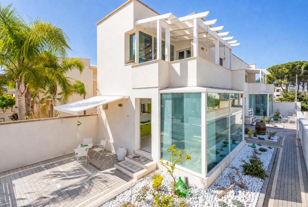 a large white house with glass doors andwindows at Viva Vacanze in Porto Cesareo