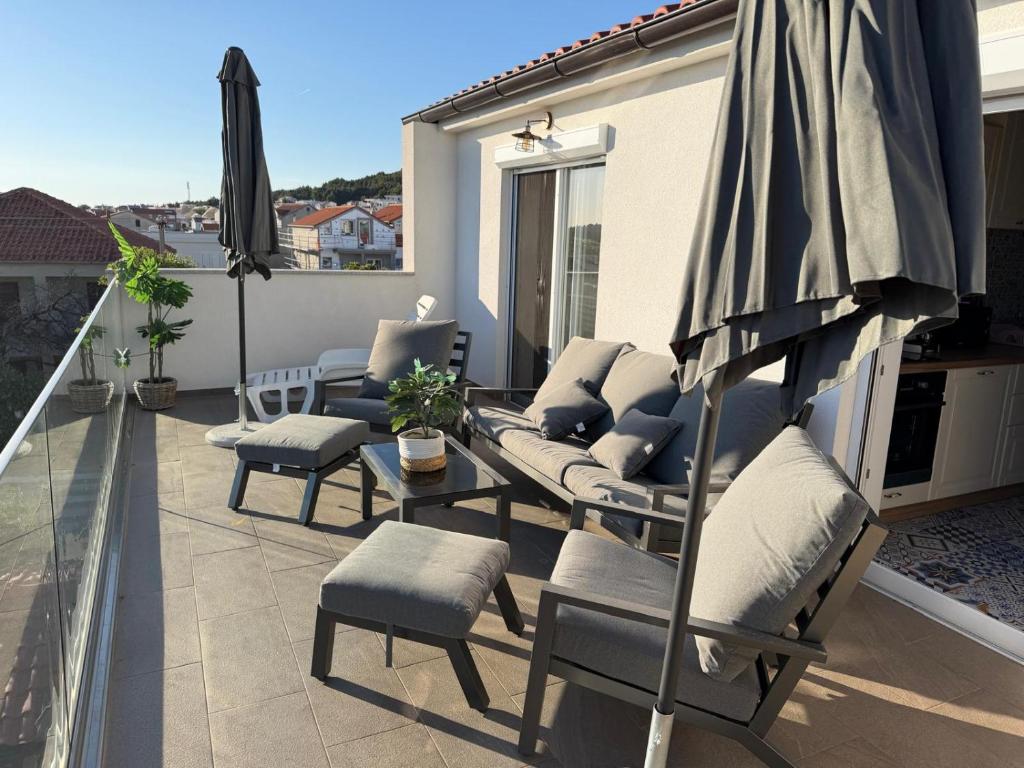 a patio with chairs and an umbrella on a balcony at Muring Apartments in Tribunj