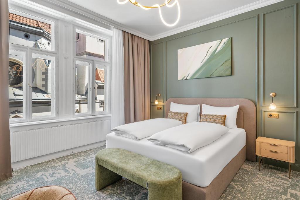 a bedroom with a bed and a chair and windows at HOME1 - Lumes Boutique Hotel in Vienna