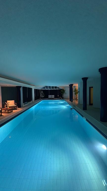 a large swimming pool in a building with blue lighting at Le jardin secret pool and spa in Lasne